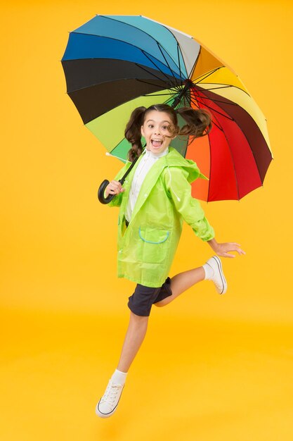 No me importa Colegiala despreocupada saltando con paraguas capa de lluvia impermeable Lluvia de otoño Días lluviosos accesorios brillantes La lluvia no es tan mala si tienes ropa resistente al agua Simple felicidad