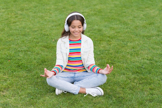 No me molestes Cool girl auriculares escuchando música Podcast educativo Escucha música mientras te relajas al aire libre Kid girl disfruta de la música prado de hierba verde Tiempo agradable Los auriculares para niños escuchan música