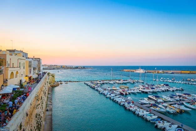 No pico da temporada turística, a multidão de turistas caminha ao pôr do sol na estrada do lado novo para o antigo da cidade de Otranto