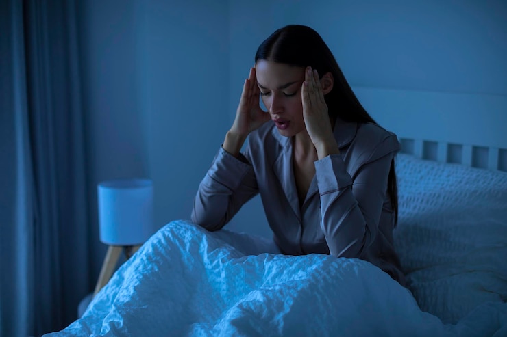 Foto no puede dormir mujer joven que sufre de dolor de cabeza o insomnio sentado en la cama despierto por la noche tocando
