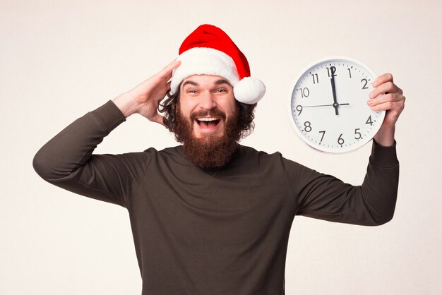 No puedo creerlo, ya es Navidad. El hombre barbudo sostiene un reloj.