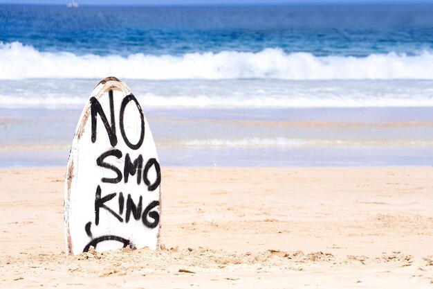 No Smoking Warnschild auf weißem Surfbrett am Strand im Sommer Konzept des Meeresumweltschutzes Design Copy Space Lifestyle