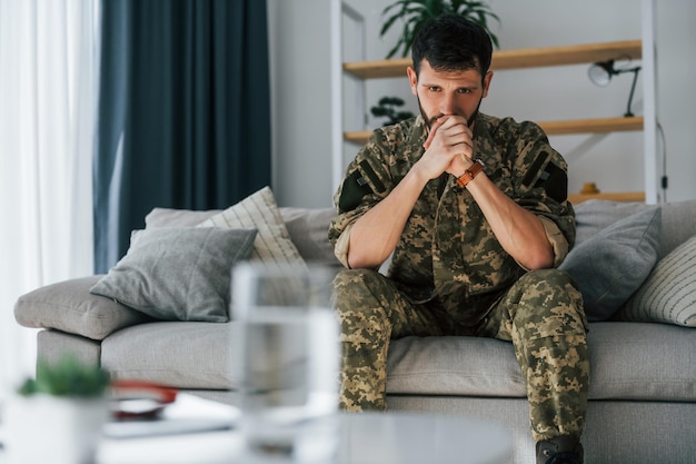 No sofá Transtorno de estresse pós-traumático Soldado de uniforme sentado dentro de casa