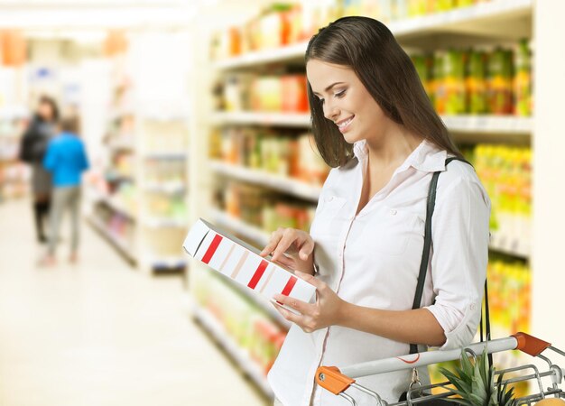 Foto no supermercado, um homem bonito usa um smartphone e olha para o valor nutricional dos produtos enlatados