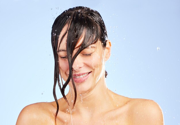 No te olvides de lavar toda la negatividad Toma de una mujer joven lavándose el cabello en la ducha contra un fondo azul