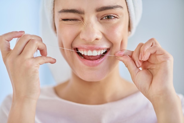 Foto no te olvides de usar hilo dental retrato recortado de una hermosa joven que usa hilo dental en el baño en casa