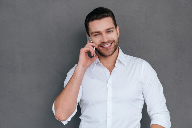 No telefone. Jovem bonito falando no celular e sorrindo