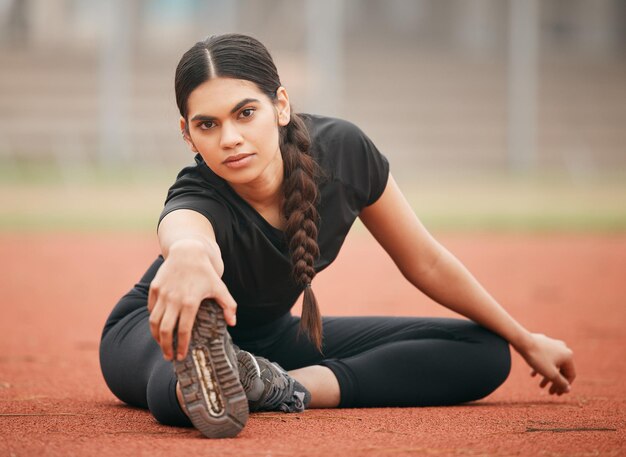 Foto no tienes que ser el mejor, solo tienes que dar lo mejor de ti. toma de una joven atlética que se estira mientras está en la pista.