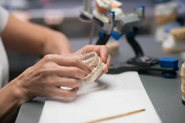 Foto no trabalho. uma mulher trabalhando com gesso médico e fazendo próteses dentárias