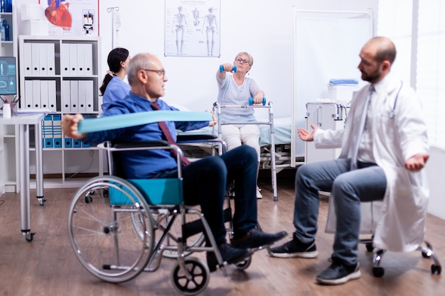 No válido en silla de ruedas ganando fuerza muscular trabajando en el centro de rehabilitación con el médico