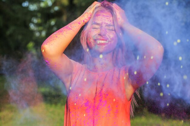 Noble blonde Frau mit explodierender bunter Farbe, die das Holi-Festival feiert