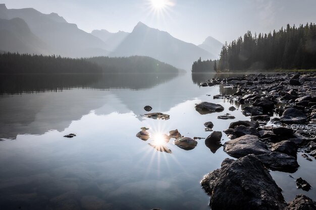 Noch alpiner See, der die Sonne und die umliegenden Berge und Wälder Jasper NP Kanada widerspiegelt