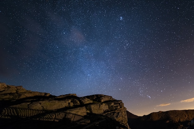 Noche en los Alpes bajo el cielo estrellado y los majestuosos acantilados rocosos en los Alpes italianos