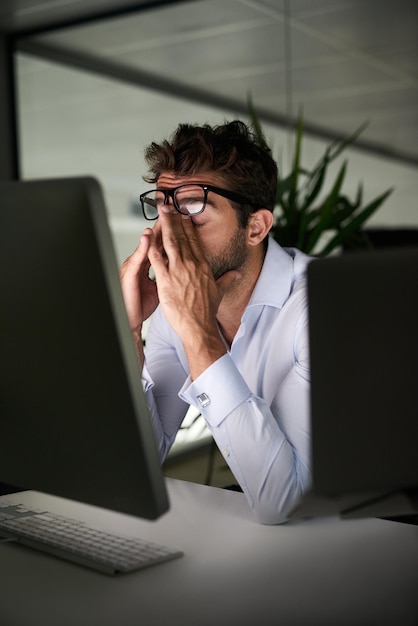 Foto noche cansada y un hombre de negocios con dolor de cabeza en la fecha límite de trabajo agotado y frustrado problema de estrés y un empleado corporativo en una oficina oscura con ansiedad o depresión de un correo electrónico en una pc