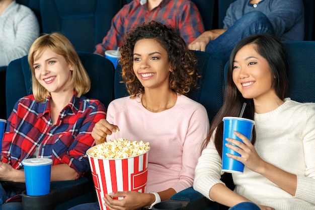 Noche de chicas. Hermosas chicas jóvenes comiendo palomitas y viendo una película juntos