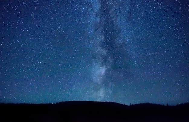 Noche cielo azul oscuro con muchas estrellas y galaxia de la vía láctea sobre una montaña