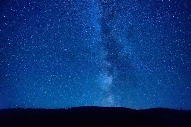 Noche cielo azul oscuro con muchas estrellas y galaxia de la vía láctea sobre una montaña