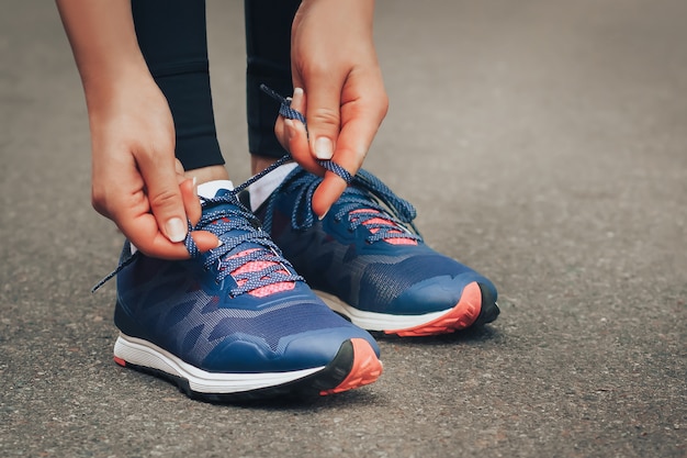 Por la noche correr Señora joven que corre en un camino rural durante puesta del sol en las zapatillas de deporte azules