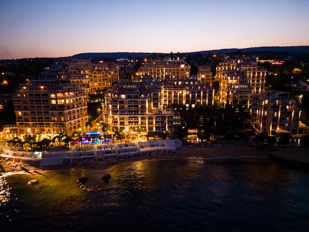 Por la noche, un dron revela un lujoso hotel balneario en la costa de Bulgaria. Las luces crean un ambiente mágico de calidez y lujo.