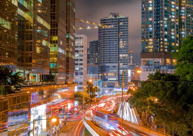 Noche de Hong Kong. Rascacielos y árboles verdes. Tráfico fuerte