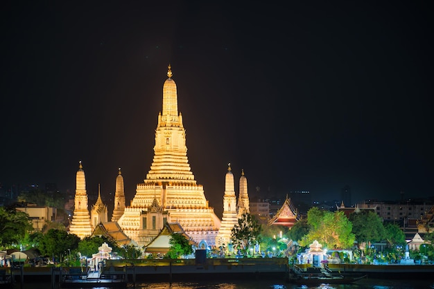 Noche iluminada Templo del Amanecer o Wat Arun y su reflejo en el río Chao Phraya después del atardecer Bangkok Thailand