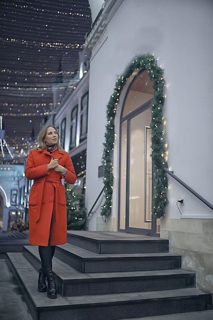 noche de invierno en las luces de la ciudad / niña adulta en un paseo de abrigo en la ciudad, imagen elegante y de moda de una hermosa modelo