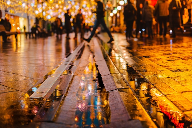 Noche lluviosa en una gran ciudad, reflejos de luces en la superficie de la carretera mojada.