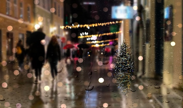 Noche de Navidad lluviosa gente de la luz de la calle de la ciudad con sombrillas a pie del casco antiguo medieval de Tallin