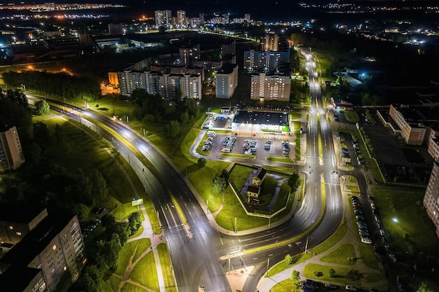 Noche sobre cruce de carreteras intersección carretera con coches con faros en la vida nocturna de la autopista en la gran ciudad mirando hacia abajo en el tráfico