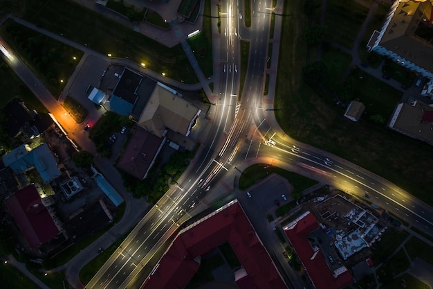 Noche sobre cruce de carreteras intersección carretera con coches con faros en la vida nocturna de la autopista en la gran ciudad mirando hacia abajo en el tráfico