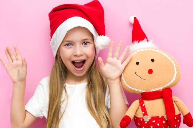 ¡Nochebuena! Un niño alegre con un sombrero de Navidad sobre un fondo rosa.