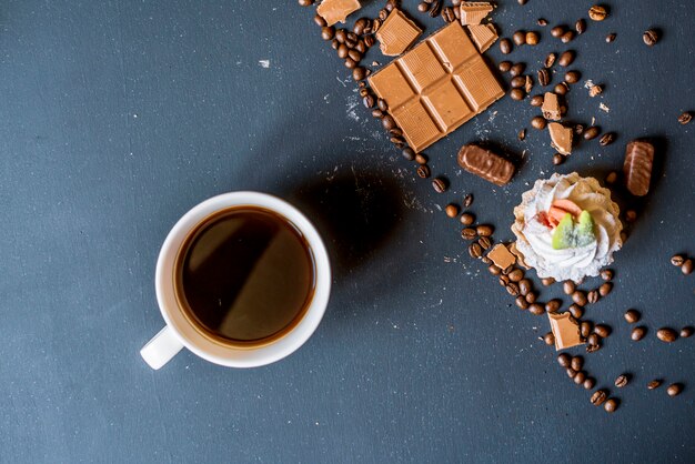 Noite café com doces e biscoitos na mesa escura