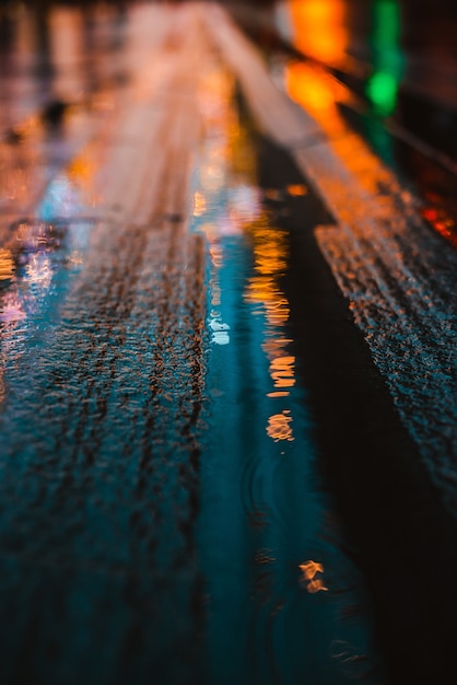 Foto noite chuvosa em uma cidade grande, reflexos das luzes na superfície da estrada molhada.