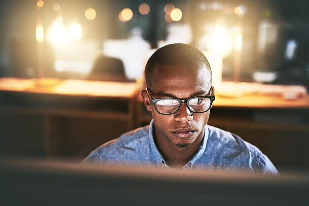 Noite computador e negócios homem preto com óculos para pesquisa de site e leitura de notícias no escritório Desenvolvedor corporativo e trabalhador on-line para atualização de software rede e trabalhando em design web