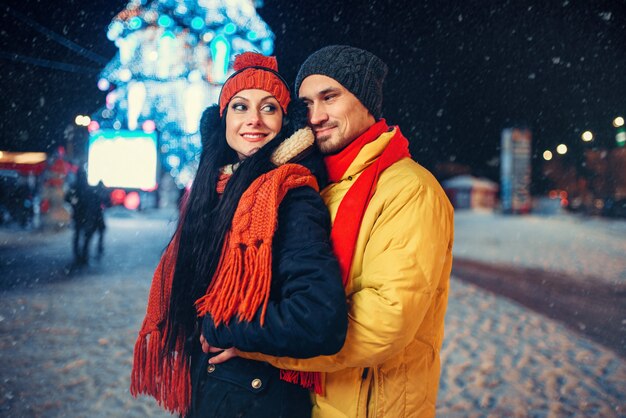 Noite de inverno do amor casal ao ar livre, iluminação de férias. Homem e mulher tendo um encontro romântico na rua da cidade com luzes