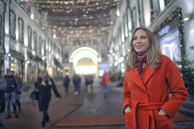 noite de inverno nas luzes da cidade / garota adulta em um casaco andando na cidade, elegante imagem elegante de uma bela modelo