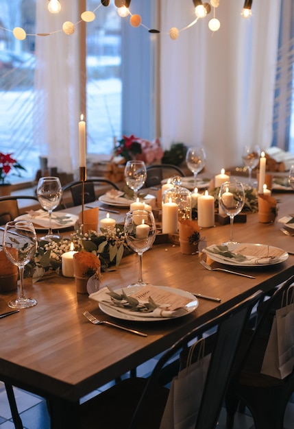 Noite de Natal. Design de mesa elegante servindo velas guirlandas de eucalipto e pratos brancos