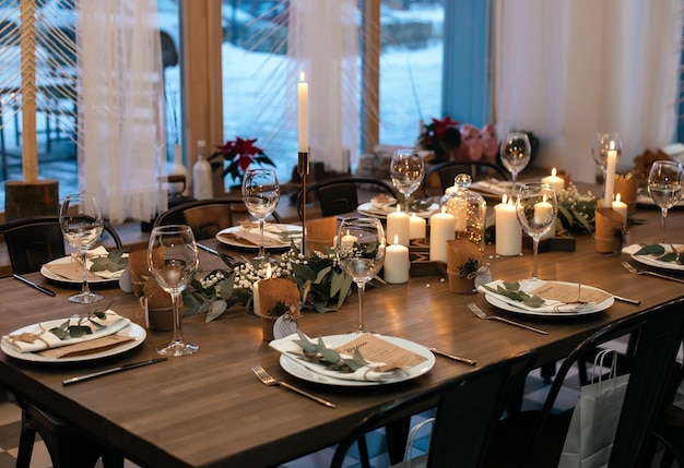 Noite de Natal. Design de mesa elegante servindo velas guirlandas de eucalipto e pratos brancos