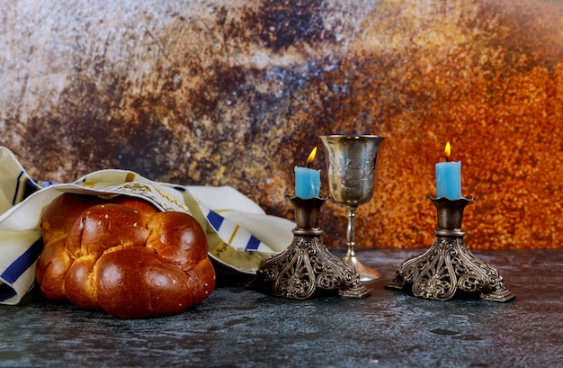 Foto noite de shabat com pão de chalá, velas de sábado e copo de vinho para crianças.