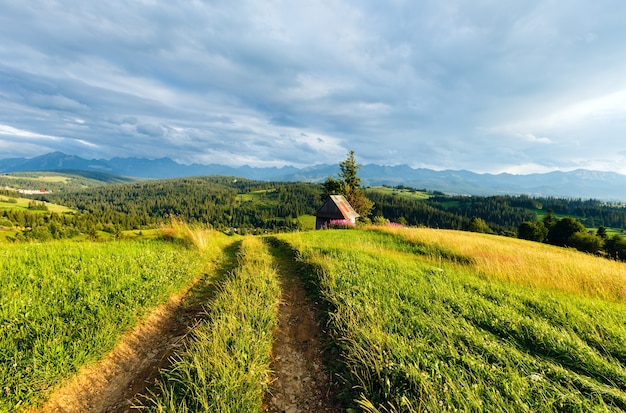 Noite de verão nos arredores de uma vila nas montanhas com uma estrada rural na frente e a cordilheira tatra atrás