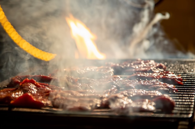 À noite, deliciosos bifes suculentos em uma fogueira são grelhados em uma churrasqueira.
