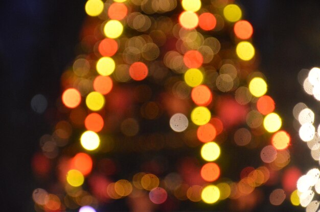 À noite e à noite a árvore de Natal brilha com luzes na cidade no inverno borrado