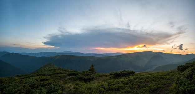 Noite enevoada sobre picos de altas montanhas e vale distante ao pôr do sol brilhante cenário incrível de encosta selvagem ao entardecer