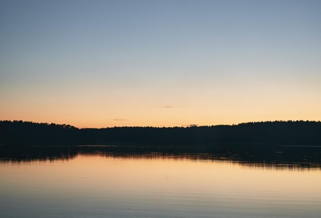 Noite no lago Fumaça na água durante o final da noite Reflexão da floresta na água com névoa