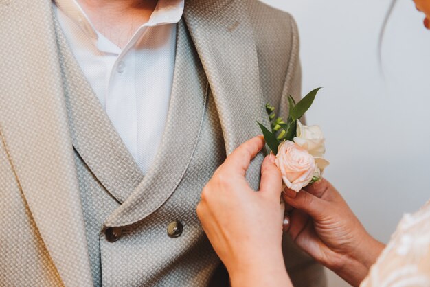 Foto noiva anexando uma flor na lapela do noivo na manhã de um casamento