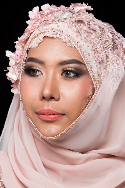 Noiva árabe muçulmana encantadora asiática em Lace Bead Bordado Sweet Pink vestido de noiva rosa rosa velho e lenço na cabeça hijab, close-up na moda maquiagem rosto de olhos, estúdio iluminação fundo preto isolado.