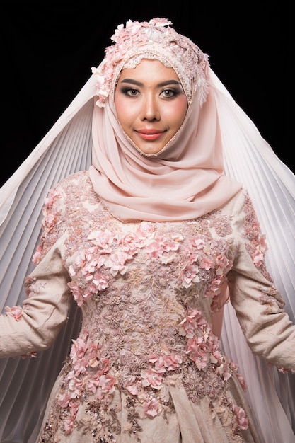 Noiva árabe muçulmana encantadora asiática em Lace Bead Bordado Sweet Pink vestido de noiva rosa rosa velho e lenço na cabeça hijab, close-up na moda maquiagem rosto de olhos, estúdio iluminação fundo preto isolado.