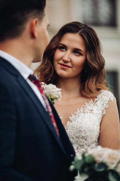 Noiva atraente em poses de vestido para a câmera com marido forte