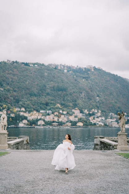 Noiva caminha pela estrada no parque olhando para o lado perto do lago Como, Itália