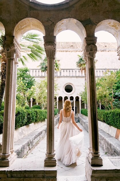 Noiva caminha pelo jardim do mosteiro franciscano Dubrovnik Croácia vista de trás